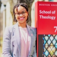 shaunesse' jacobs smiles in front of the BU School of Theology sign