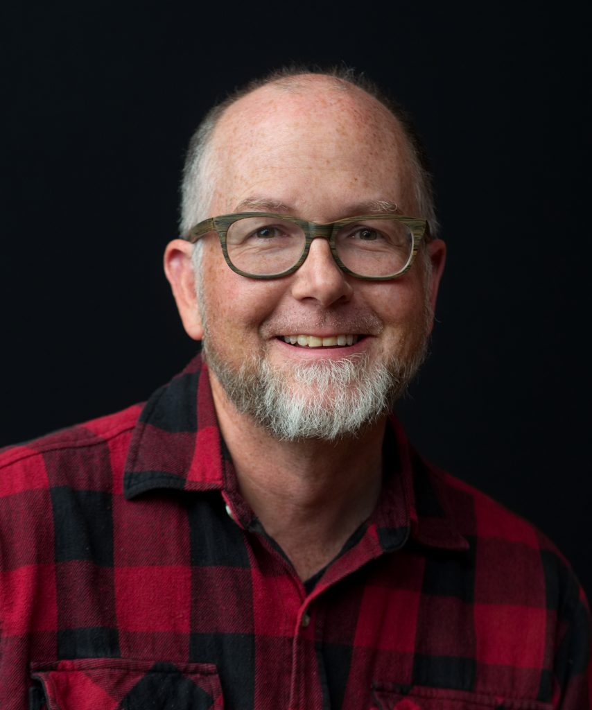 Steve Baliko smiles in front of a black background